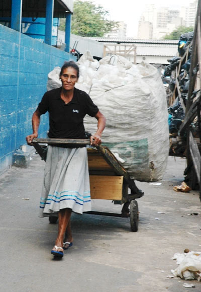 Woman waste picker pulling cart of waste in Brazil