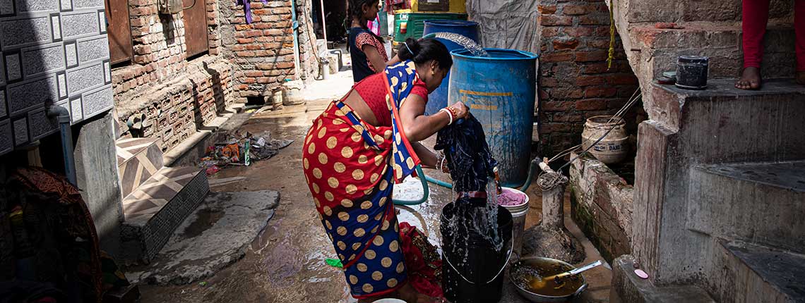 A resident of Savda Ghevra washing clothes in the narrow lane outside her home