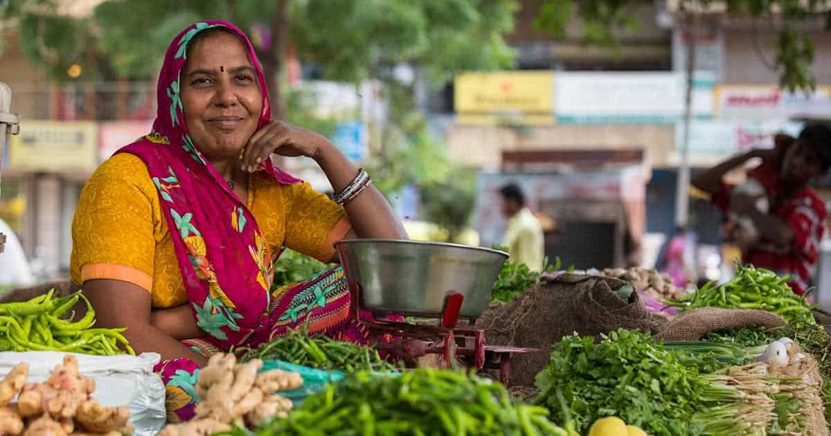 Choral Mauladia poses near her cart where she sells vegetables at a local market