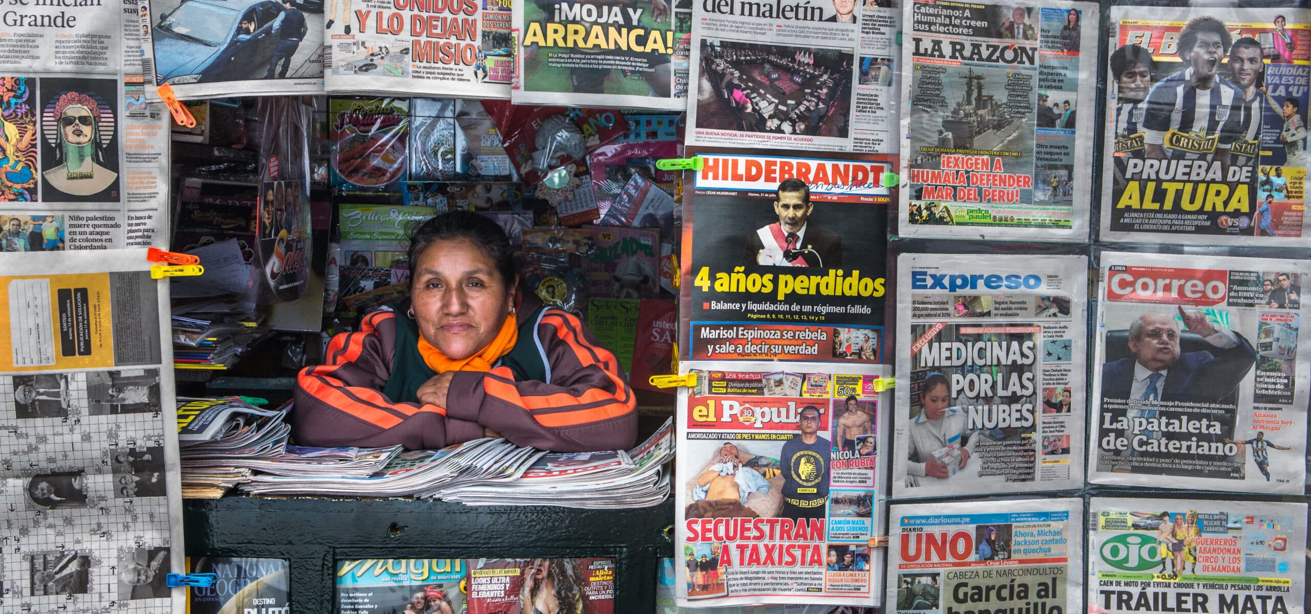 Auria Cantorín, a newspaper vendor (canillita), standing by her newsstand in Peru. She is a member of FENVENDRELP, an organization that has negotiated collective agreements benefiting vendors, including funeral and burial expenses.