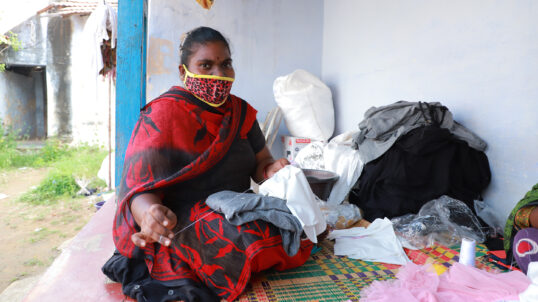 Una trabajadora textil cose en Tiruppur, India, durante la pandemia de la COVID-19.