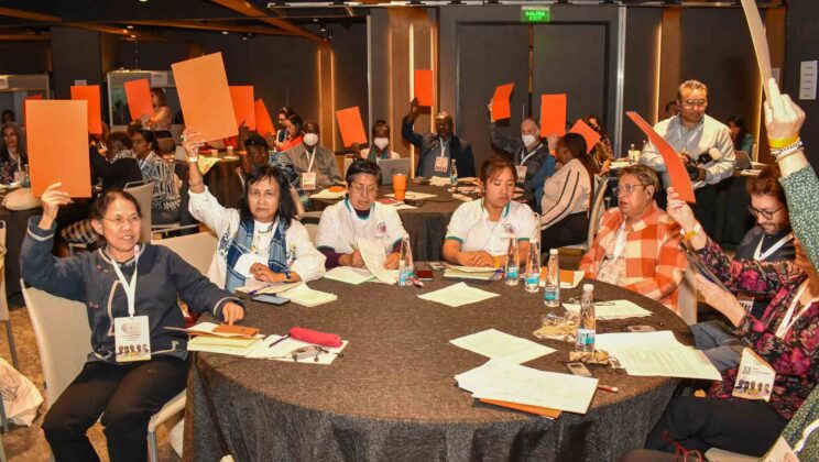 Institutional Members voting to adopt the strategic plan at WIEGO's 2022 General Assembly, with participants raising their hands in support