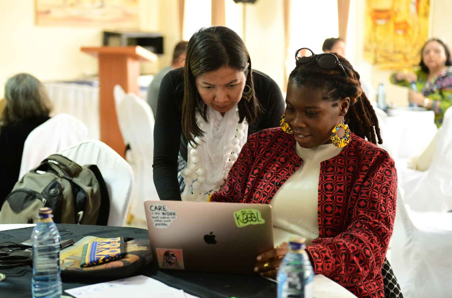 WIEGO team members working together on a laptop during a team retreat in Nairobi, Kenya, collaborating in a supportive environment.