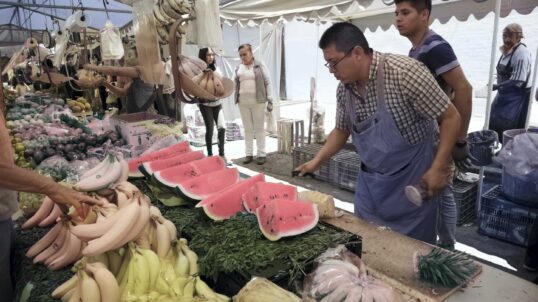 A street vendor in Mexico City prepares fresh watermelon and bananas for customers at a bustling outdoor market