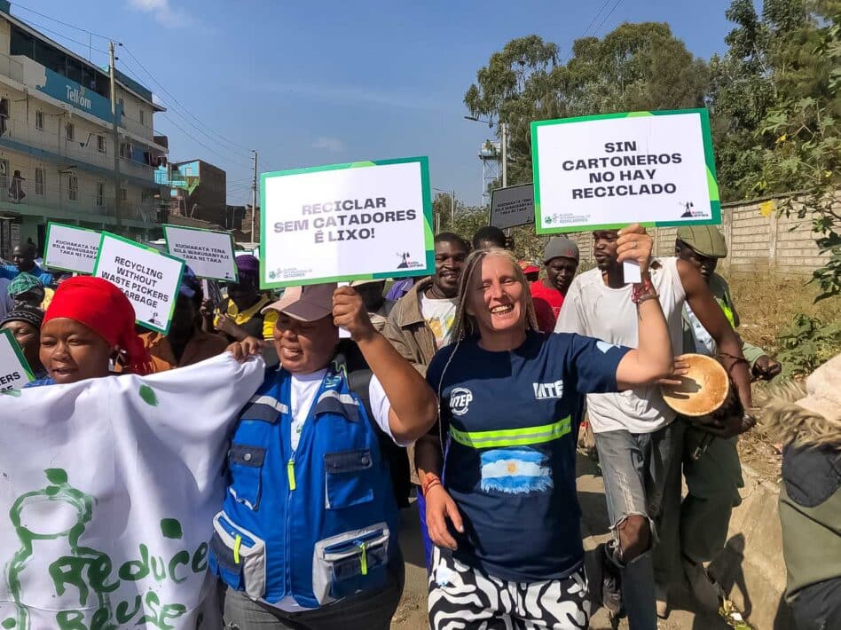 A diverse group of people marching outdoors, holding protest signs and banners advocating for waste pickers' rights.