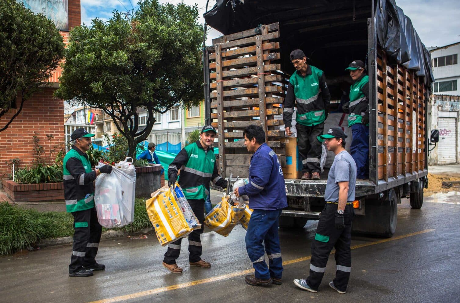 Waste pickers from ARAUS, part of ARB in Bogotá, Colombia, collect recyclables door-to-door in Puente Aranda, educating residents on recycling while loading materials onto a truck.