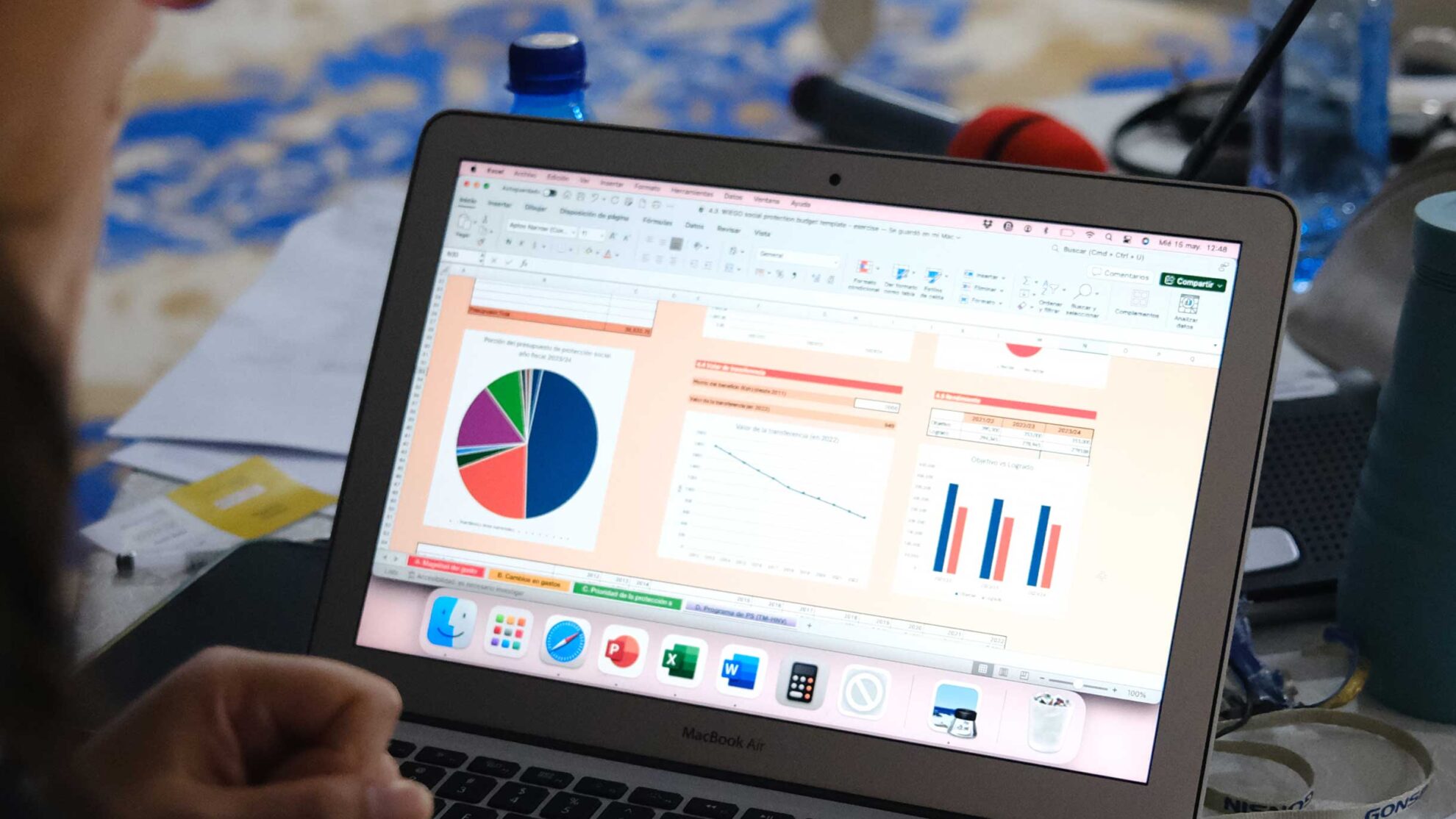 WIEGO demonstrates an online tool for calculating social protection financing, with financial charts and graphs visible on a laptop screen