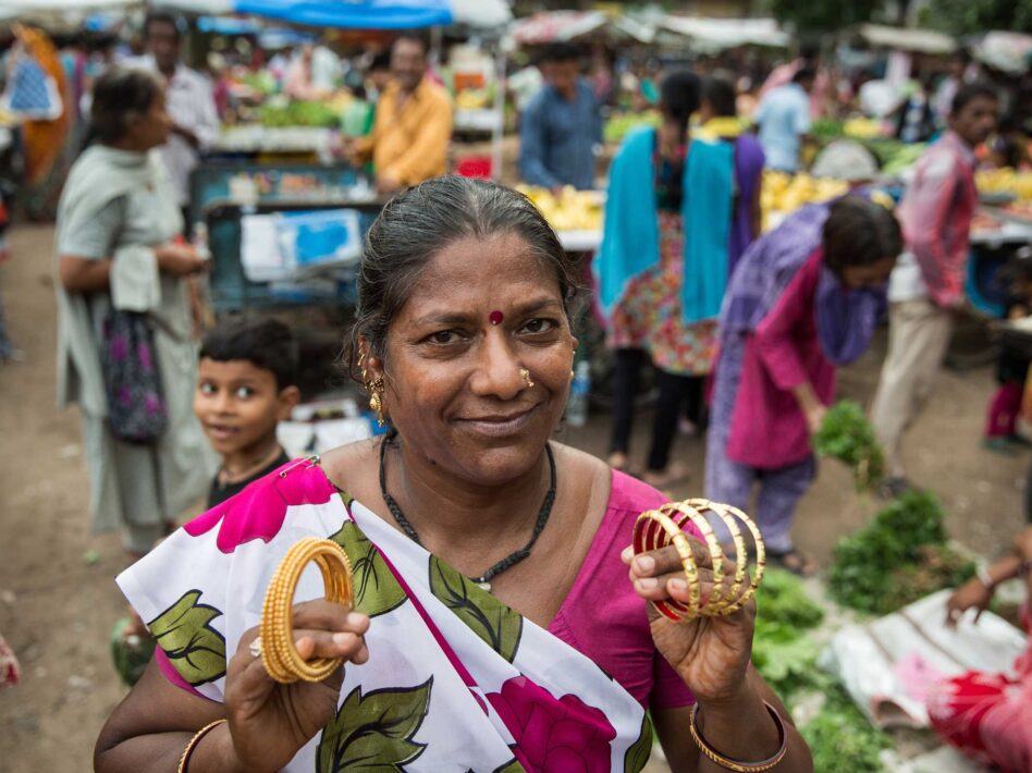 Indian woman in a sari holding bangles at a busy outdoor market in Ahmedabad.