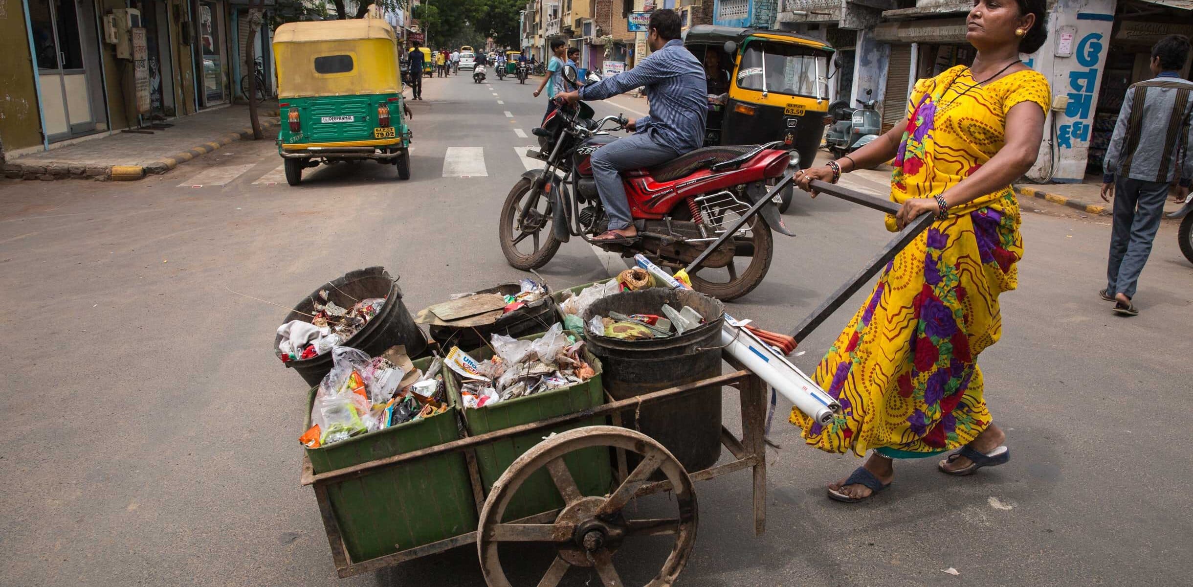 A waste picker in Ahmedabad, India, pushes a cart full of collected waste.